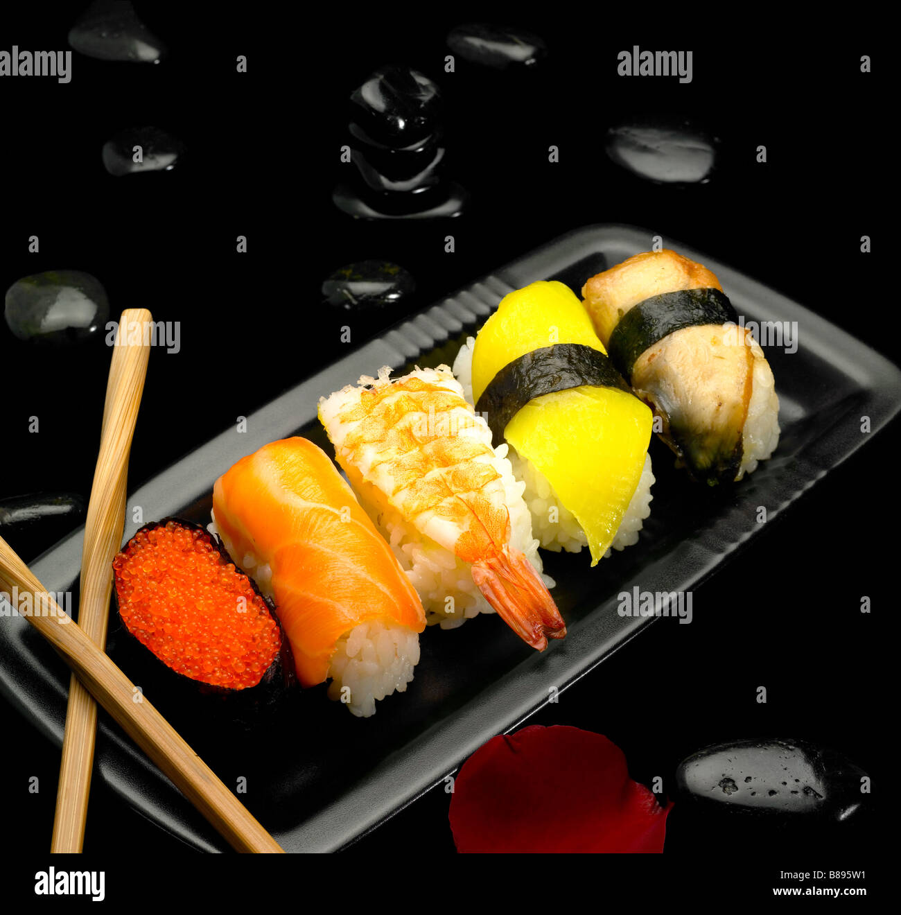 assorted sushi plate on black pebbles over black background Stock Photo