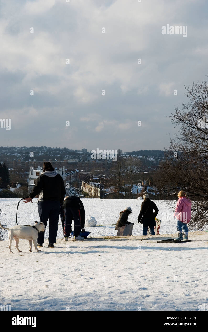People ride in a sledge in the snow down the hill in a park, on winter day, London England UK 2009 Stock Photo