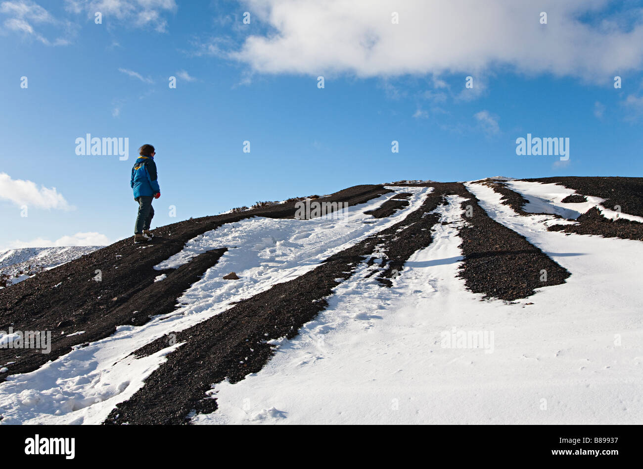 Woman walking uphill in winter Pwll Du Wales UK Stock Photo