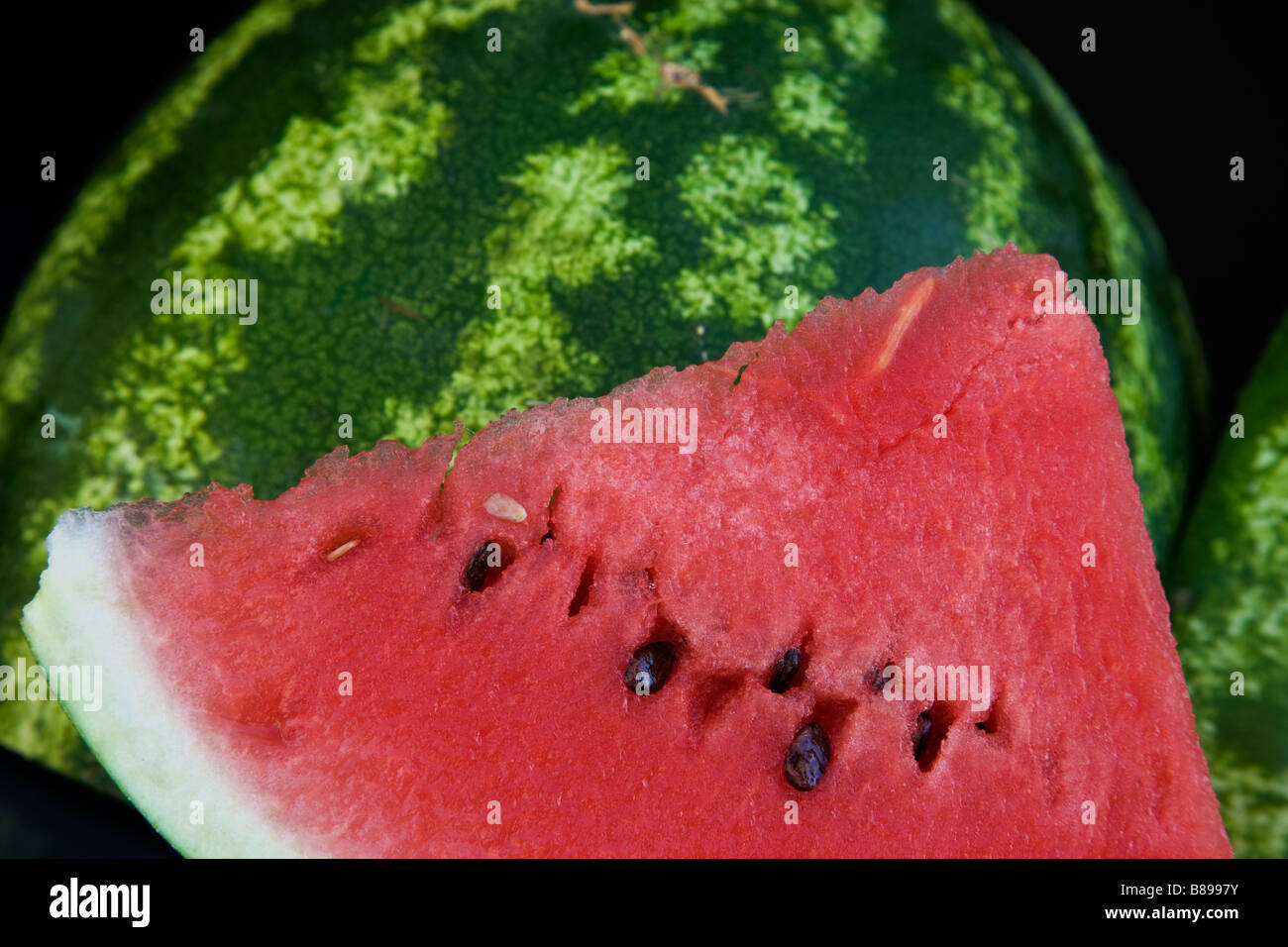 Watermelon slice against exterior of melon. Stock Photo