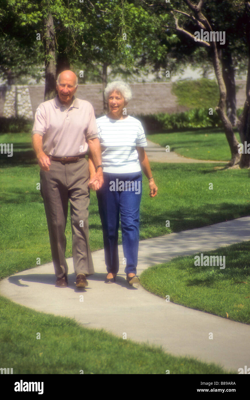 Senior couple walk hand in hand through park obesity Stock Photo - Alamy