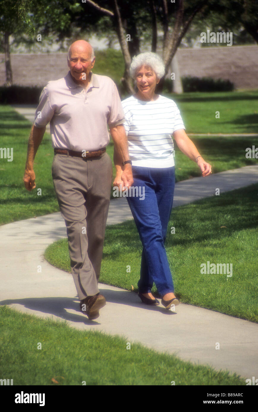 Senior couple walk hand in hand through park obesity Stock Photo - Alamy