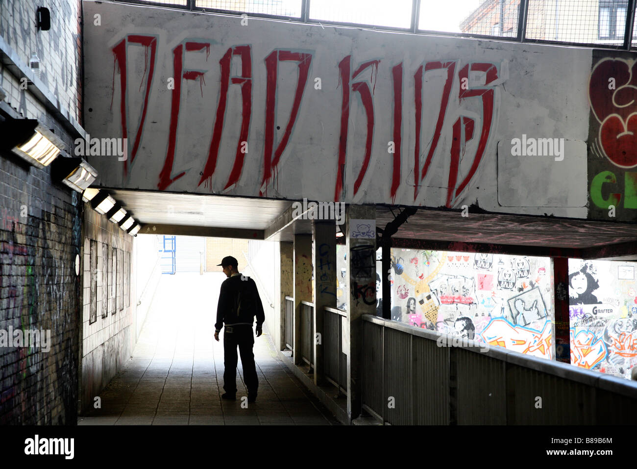 Youth walking under graffiti that reads DEAD KIDS, Leake Street, Waterloo, London Stock Photo
