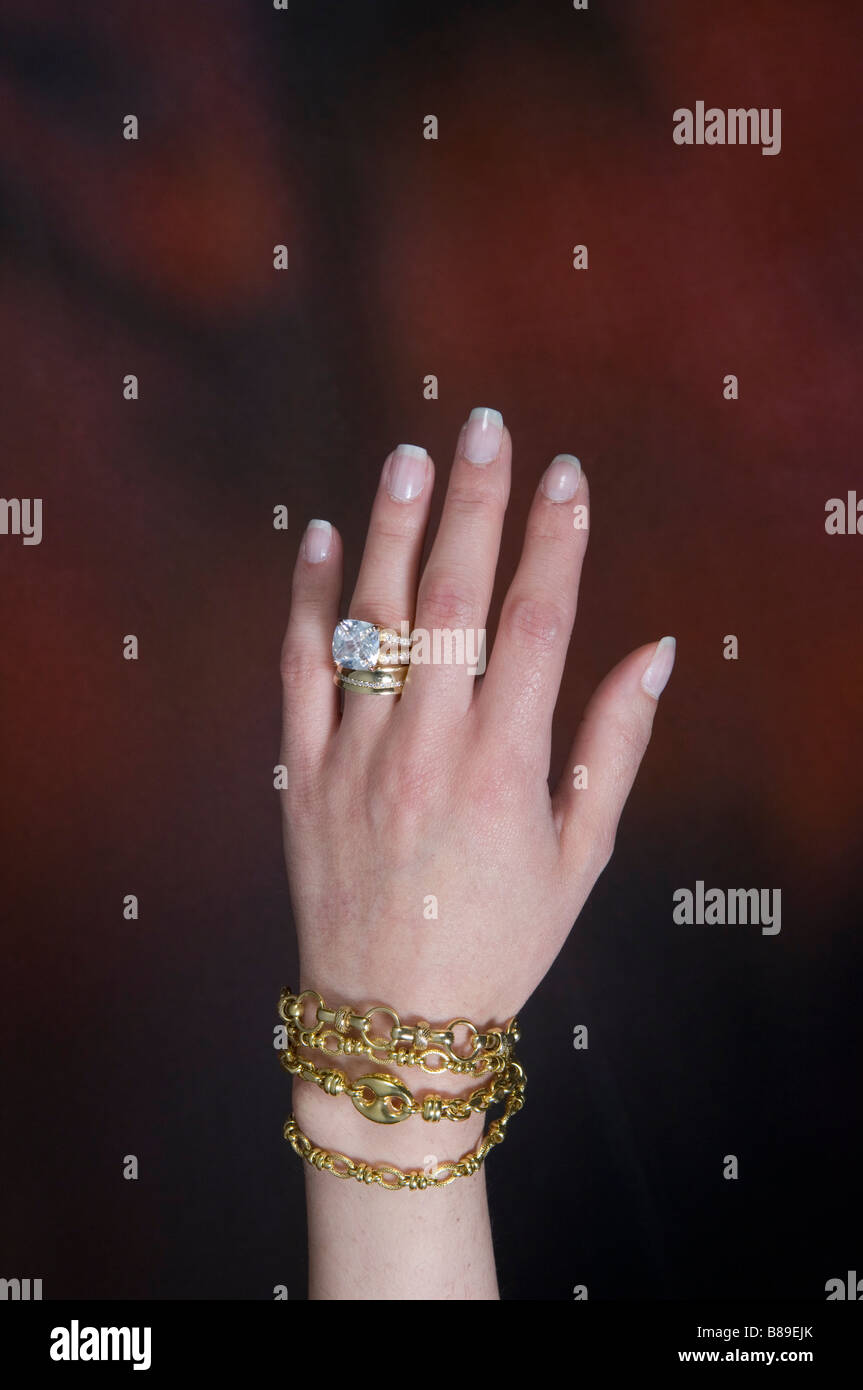 Woman's hand wearing big diamond ring and golden bracelets Stock Photo