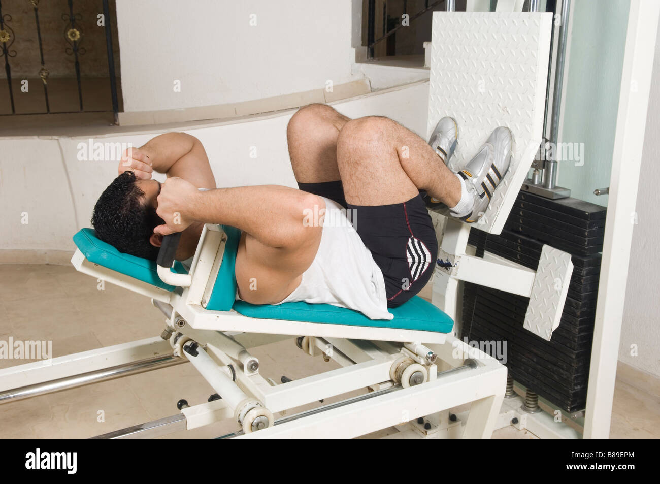 Man exercising on a leg press machine in the gym Stock Photo