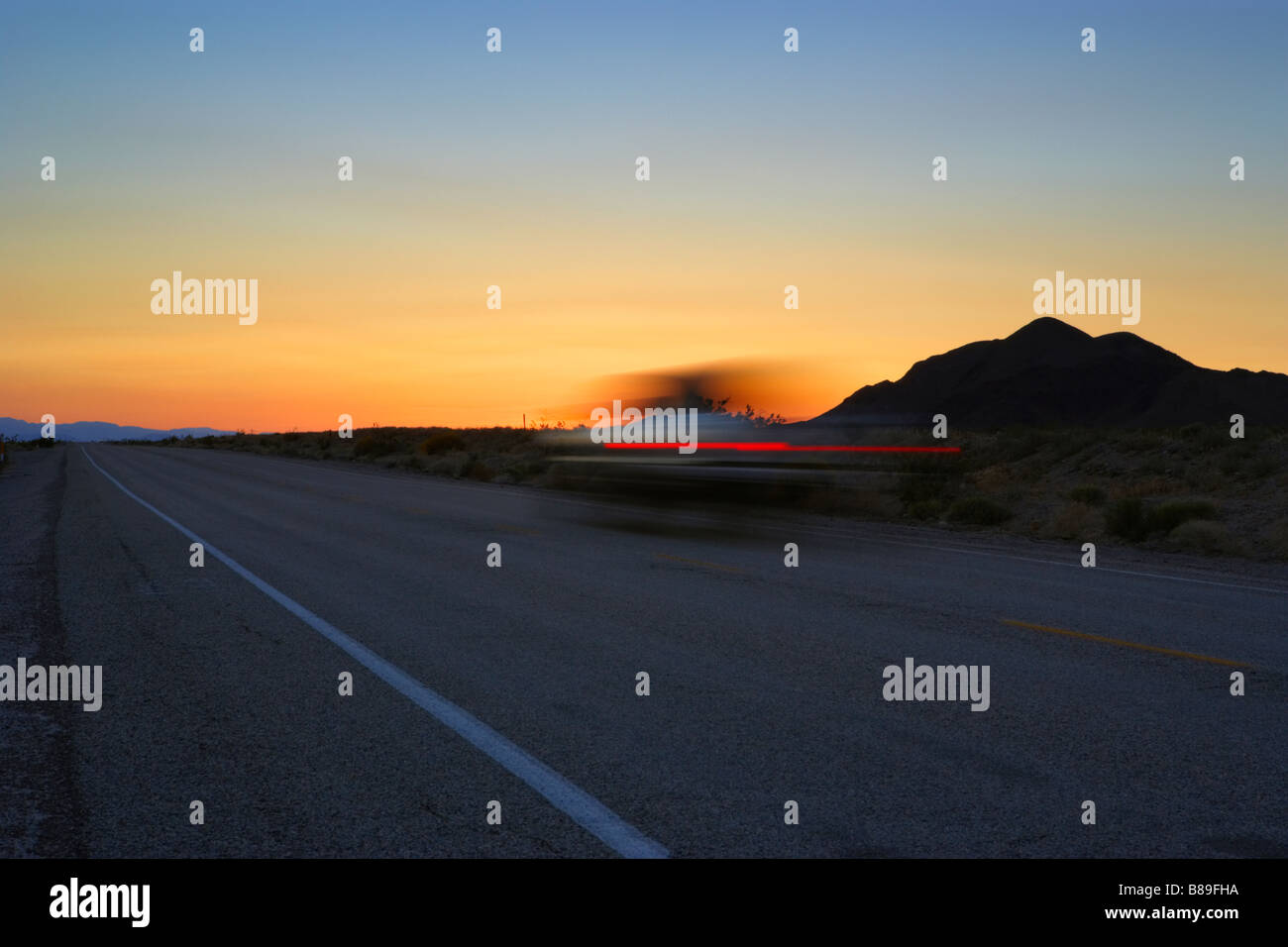 Car on desert road at dusk in Mojave Desert California United States of
