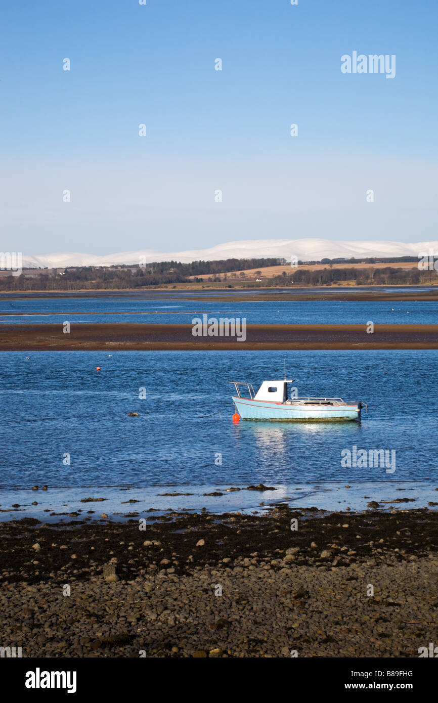 Boat anchored in Montrose Basin, with snow hills behind. Montrose, Angus, Scotland Stock Photo
