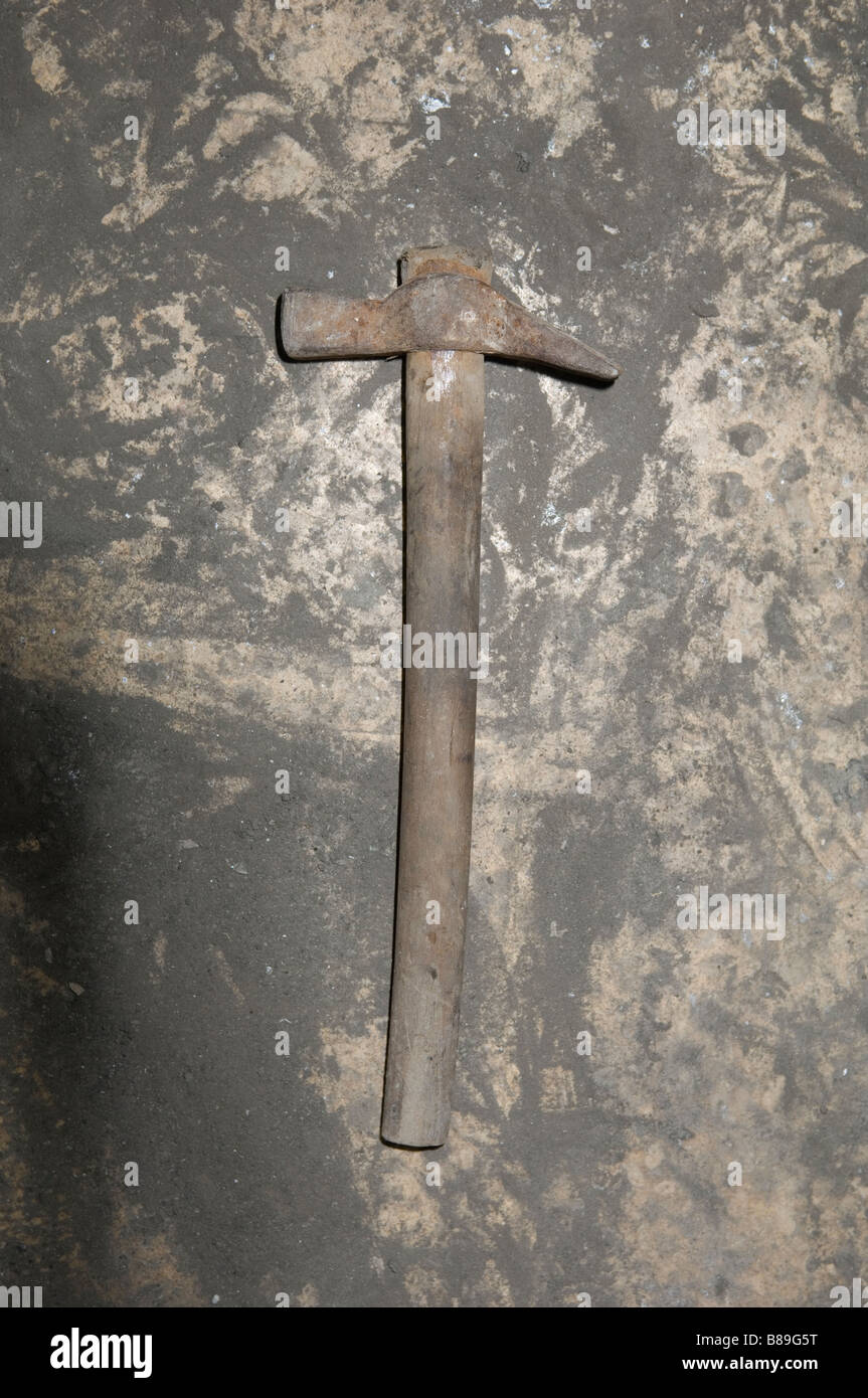 Old hammer on a dirty floor inside a garage Stock Photo