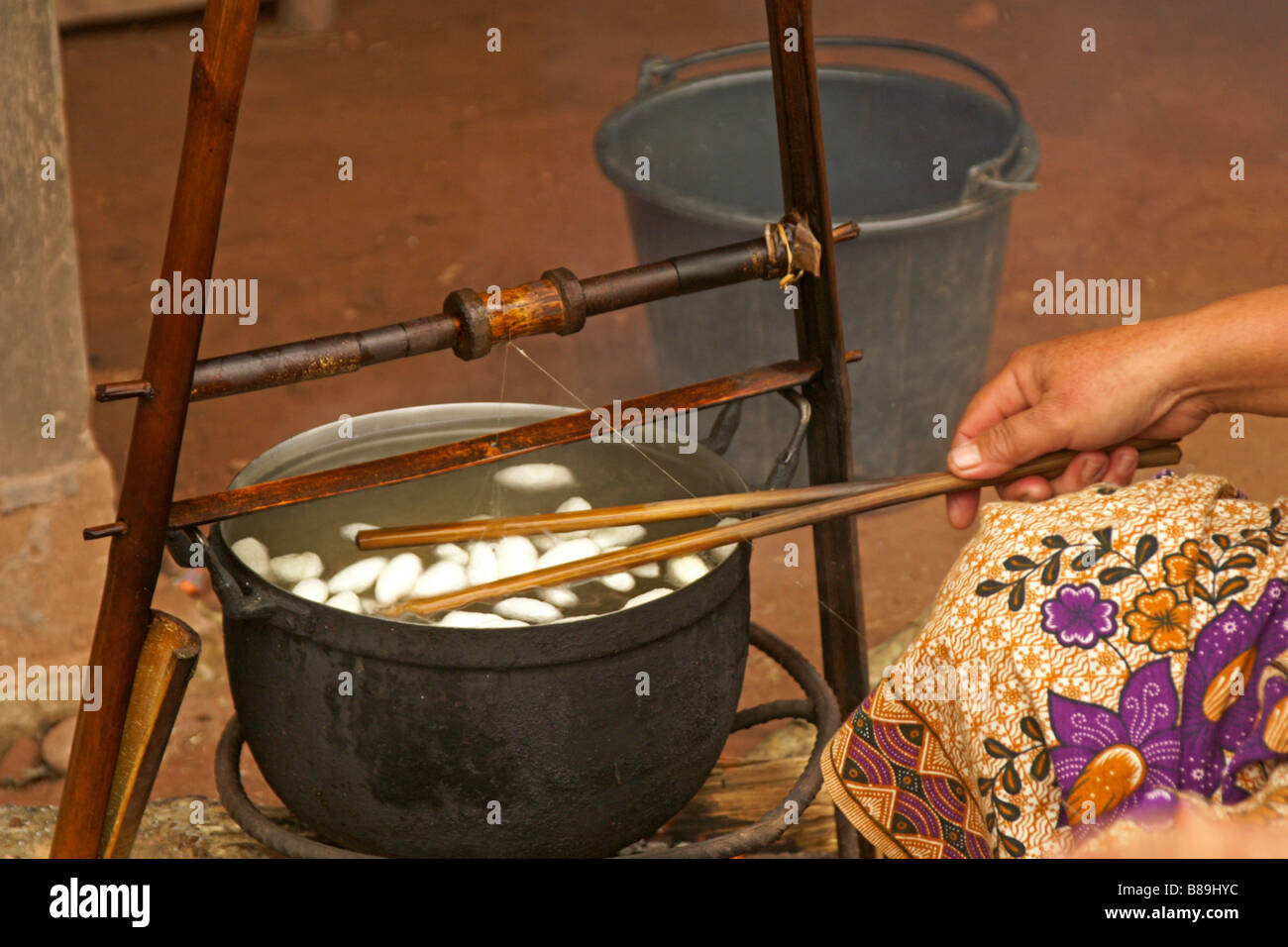 Extracting silk threads from boiled silkworm cocoons, Laos Stock Photo