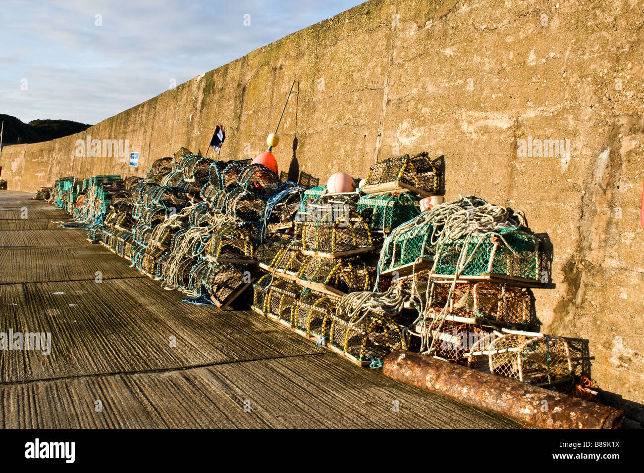 Lobster traps on a dock by a weatherbeaten stone wall in Findochty, Scotland Stock Photo