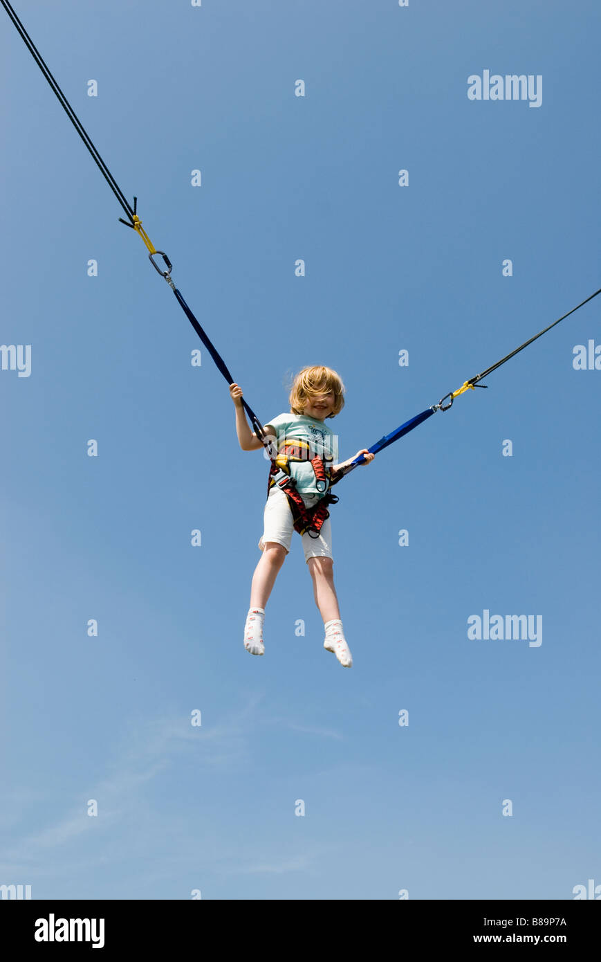 A young girl wearing a harness bouncing on a trampoline Stock Photo Alamy