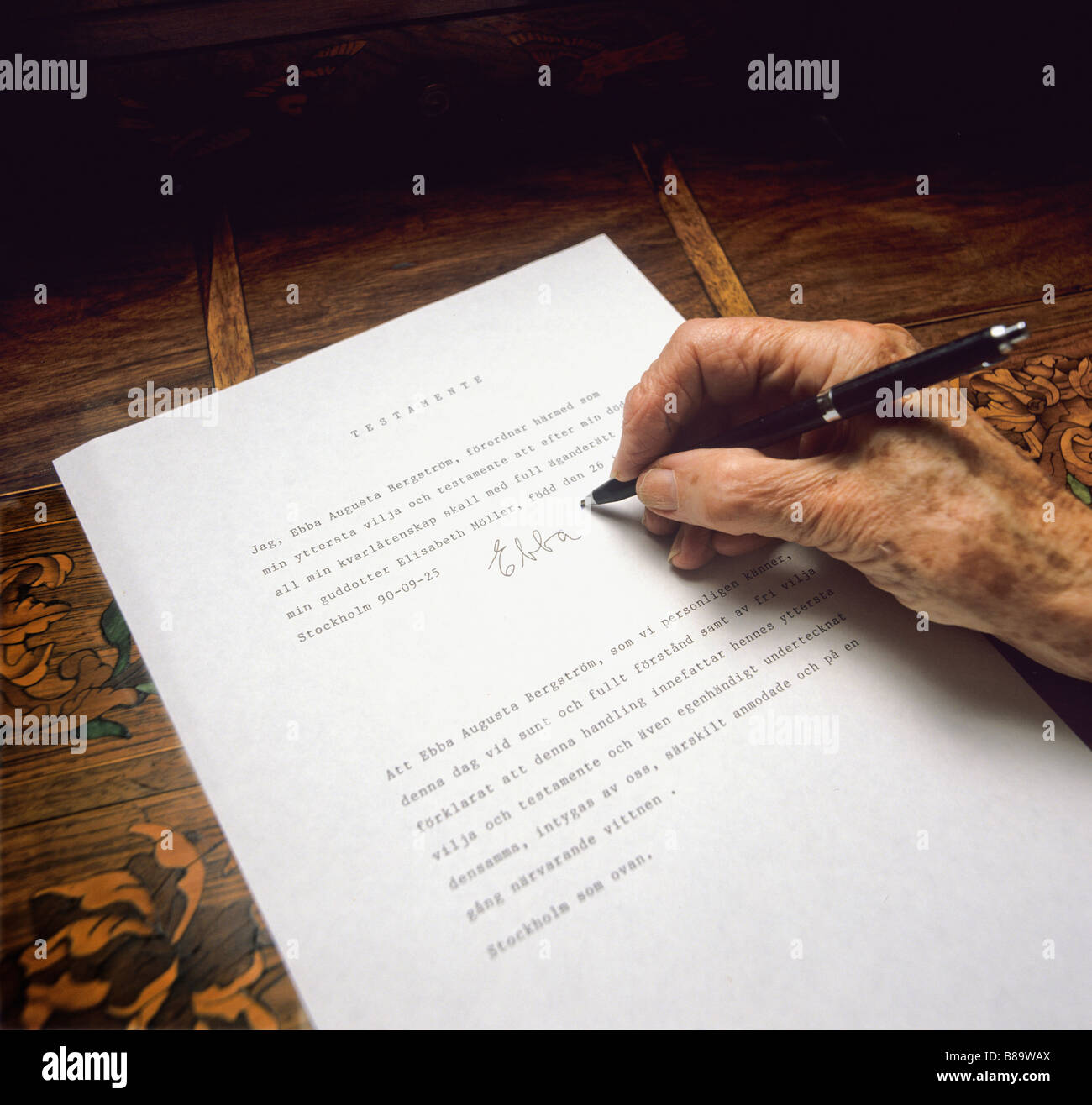 An old womans hand puts her signature on her testament Stock Photo