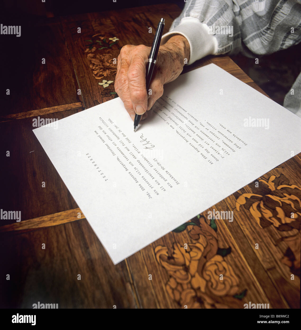 An old womans hand puts her signature on her testament Stock Photo