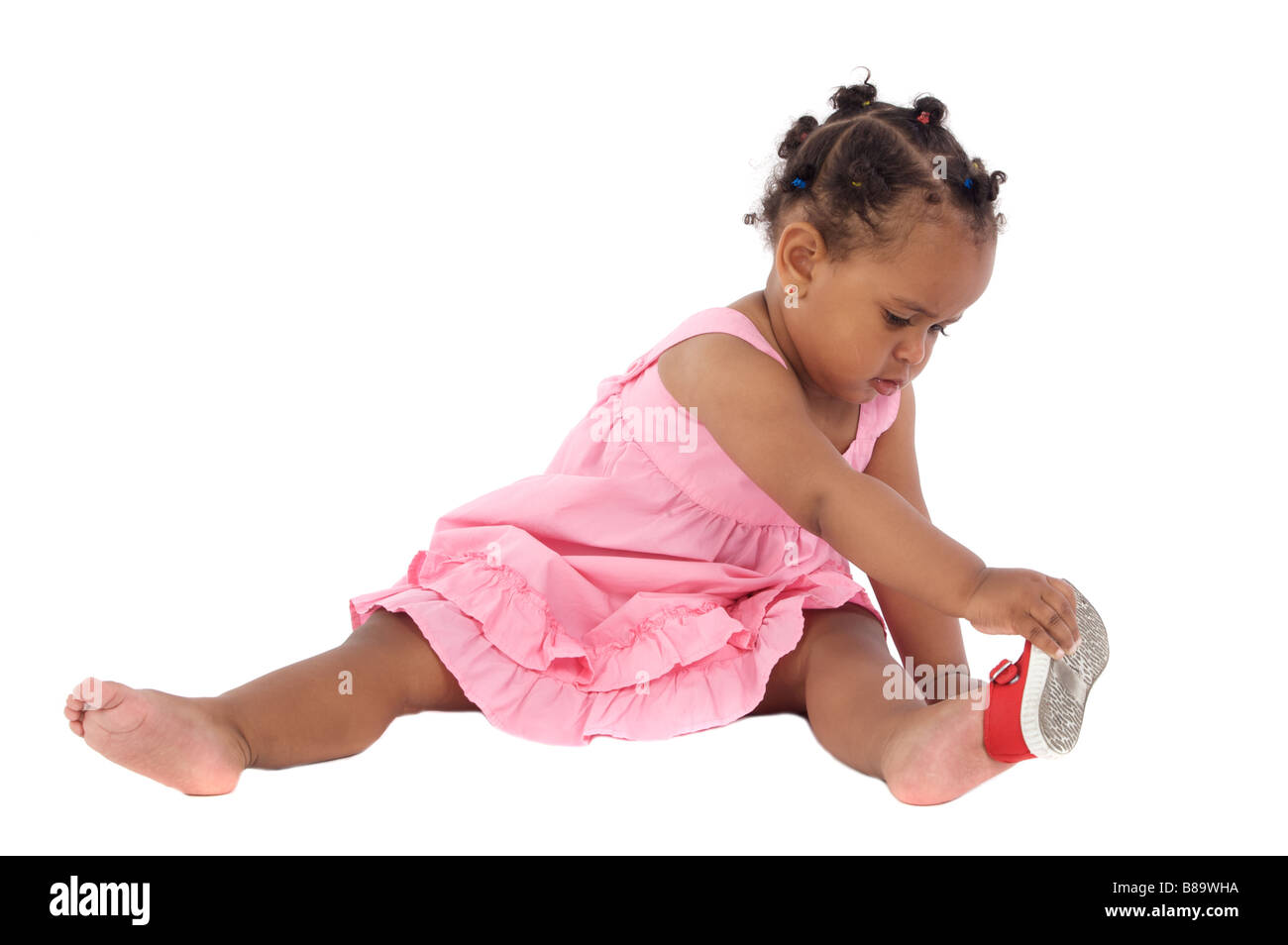 Beautiful african baby girl putting on an slipper on a white background