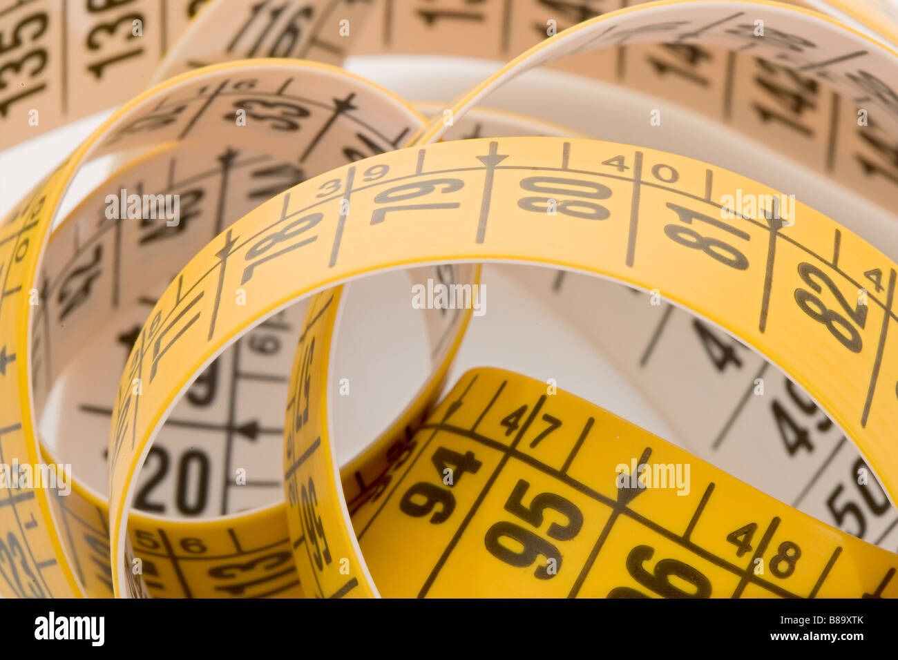 Two rolled-up white and yellow tailor measuring tape on an old wooden  surface Stock Photo - Alamy