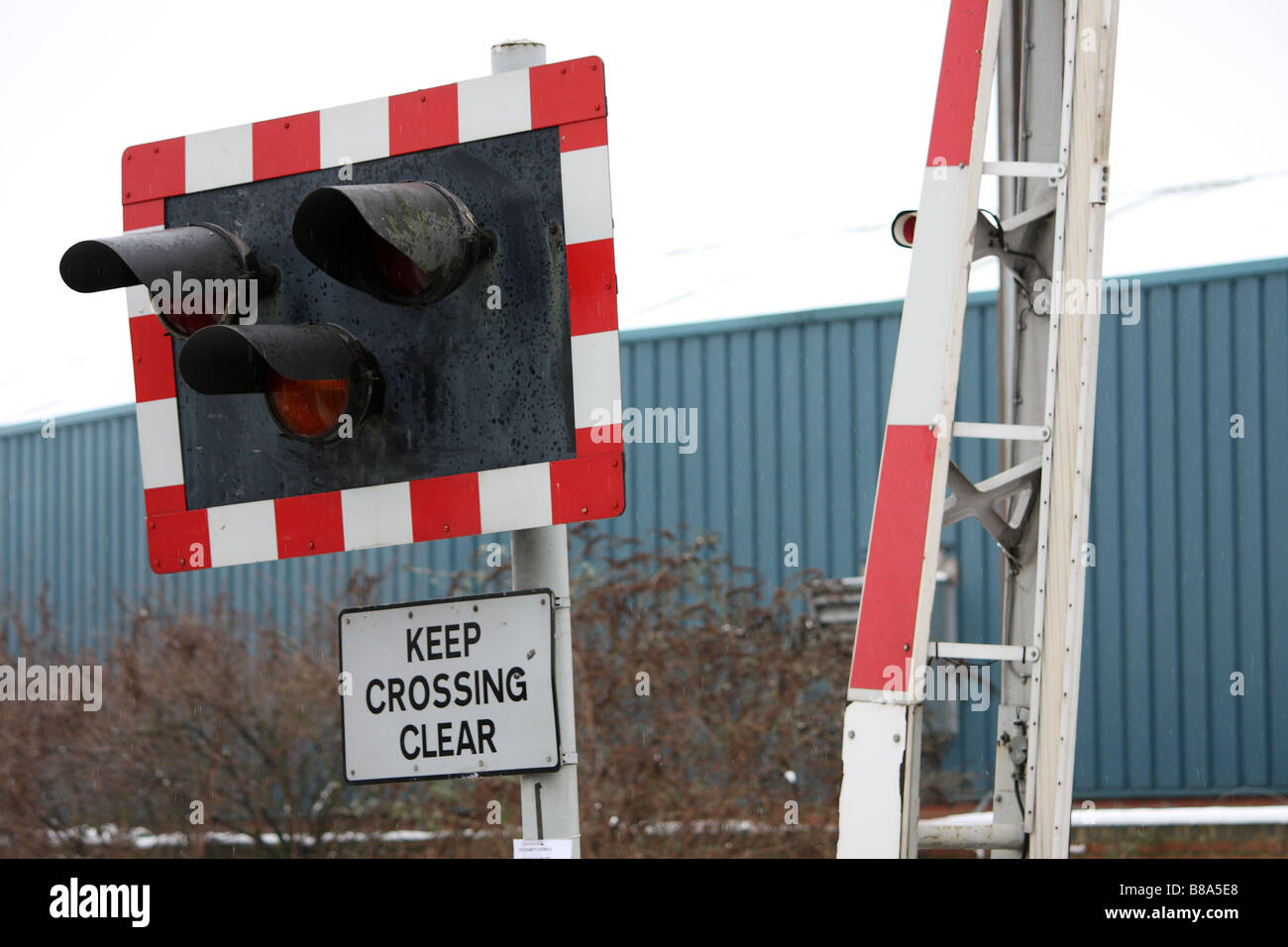 A photograph of a railway crossing lights and barrier taken from a public road Stock Photo