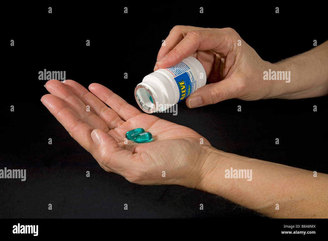 Over the counter drugs such as Aleve in the form of capsules being removed from their bottle Stock Photo