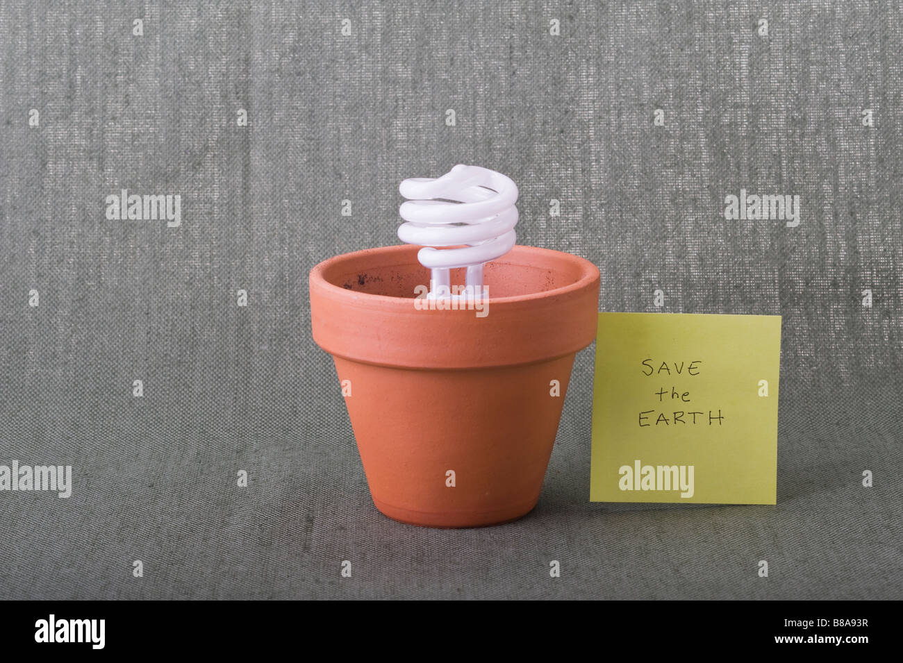 Save the Earth eco friendly energy saving compact fluorescent bulb in clay pot Earth Day climate crisis environmental responsibility concepts. Stock Photo