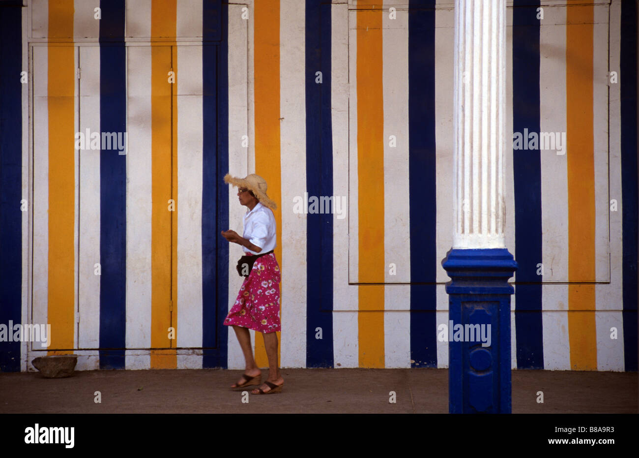 Malagasy Woman Walks Past a Boarded Up Shop in Diego Suarez or Antsiranana, northern Madagascar Stock Photo