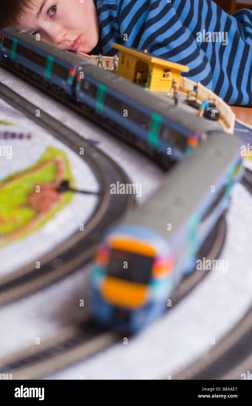 Young boy playing with a model toy electric train set in oo gauge with engines from Hornby and