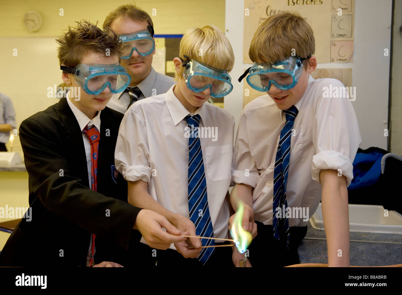 Teenage boys wearing goggles conduct an experiment with the use of a bunsen burner at a school chemistry laboratory Stock Photo
