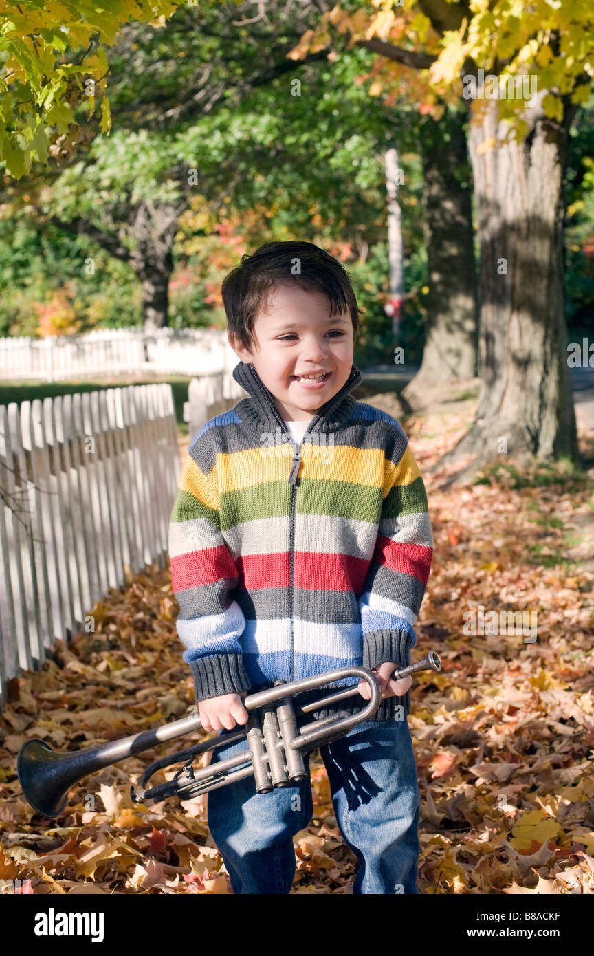 Three year old boy plays with his trumpet outside on a fall day Stock Photo
