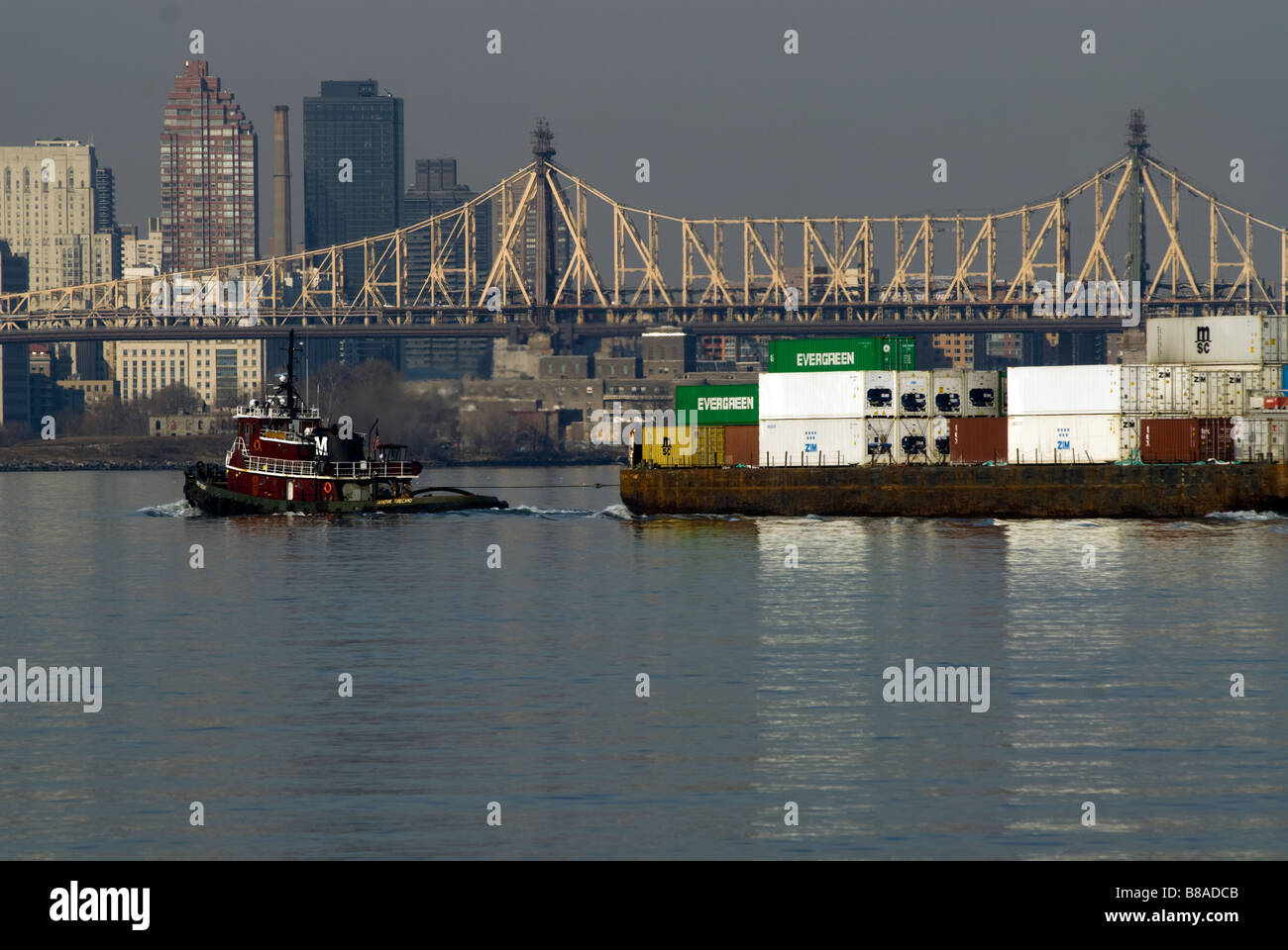 A tugboat tows a barge of containers in the East River in New York Stock Photo