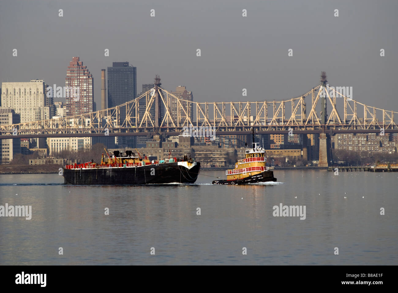 A tugboat tows a barge in the East River in New York Stock Photo