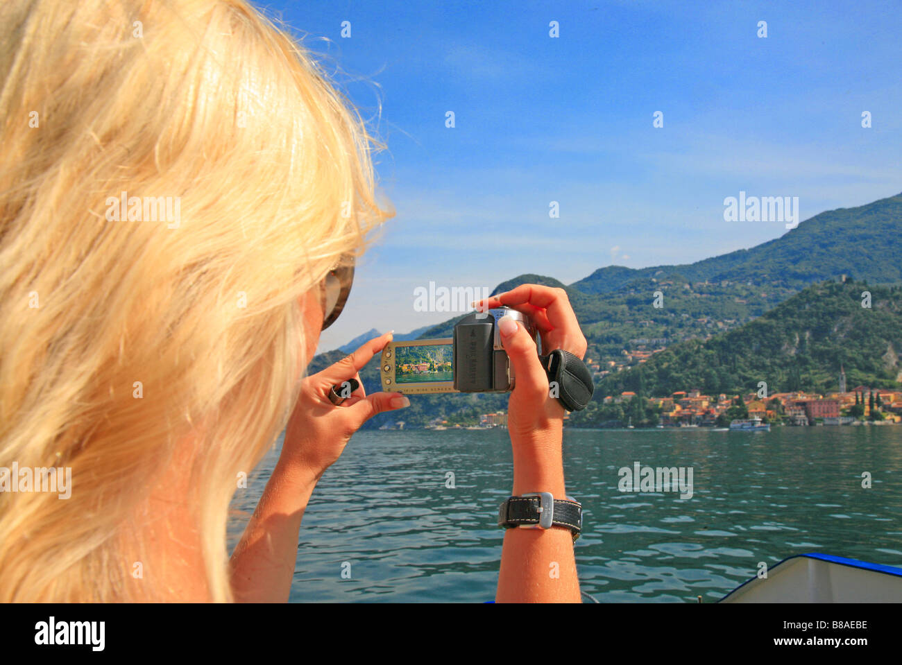 Young woman taking photograph from a passenger ferry crossing from Bellagio to Varenna on Lake Como Stock Photo