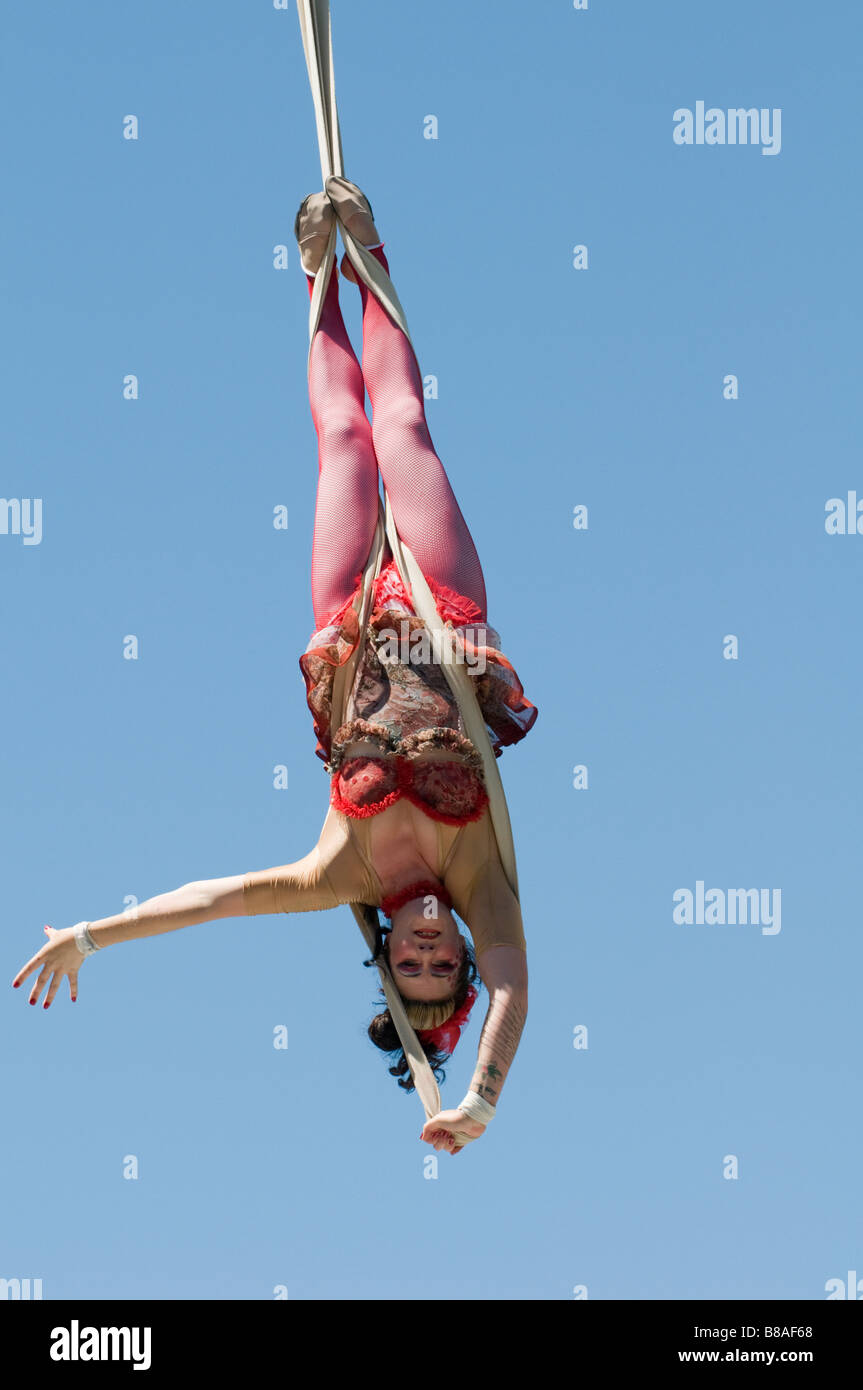 Trapeze artist hangs upside down Stock Photo
