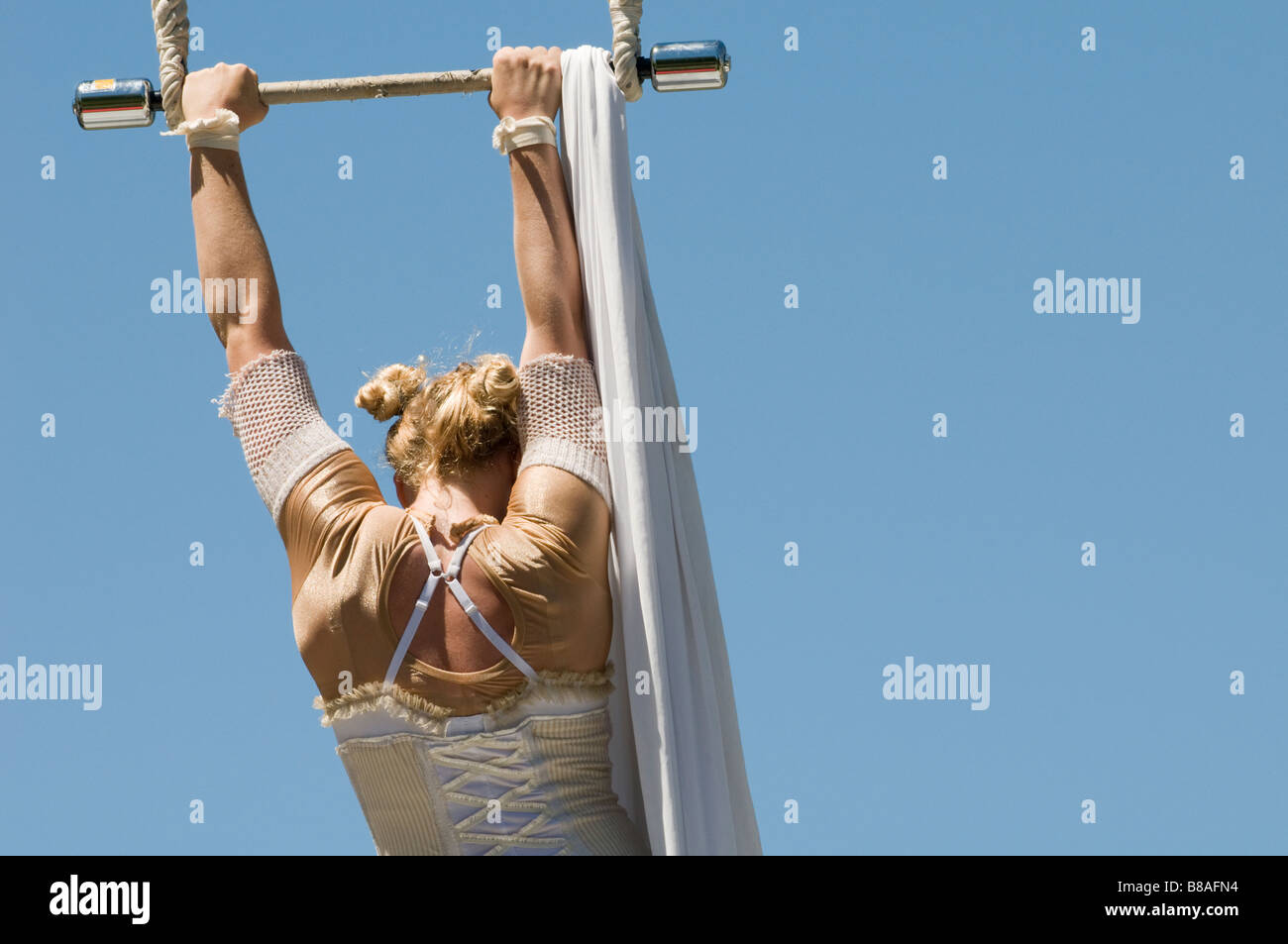 Female trapeze artist grips the bar Stock Photo