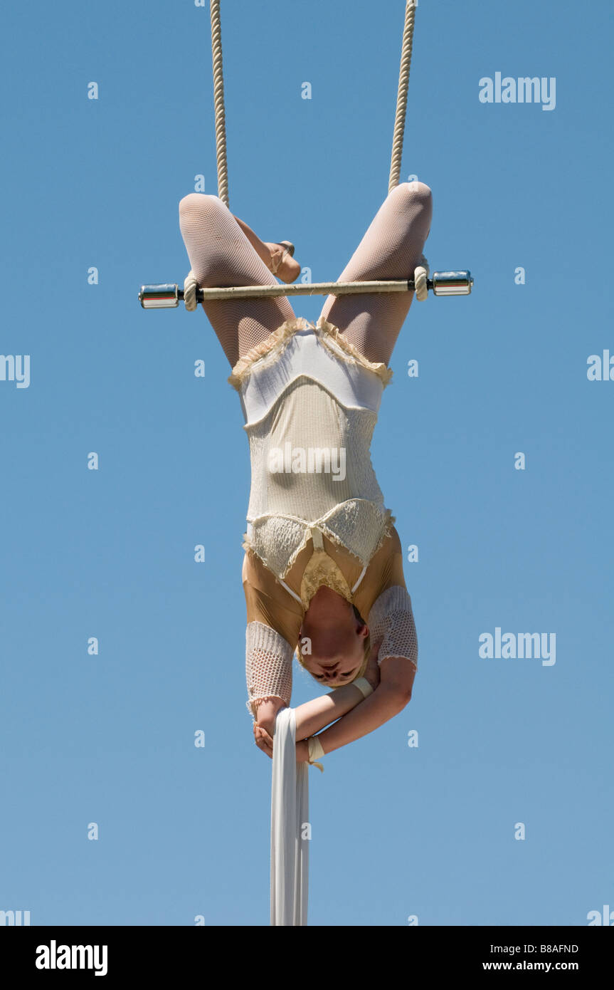 Female trapeze artist hangs from swing Stock Photo