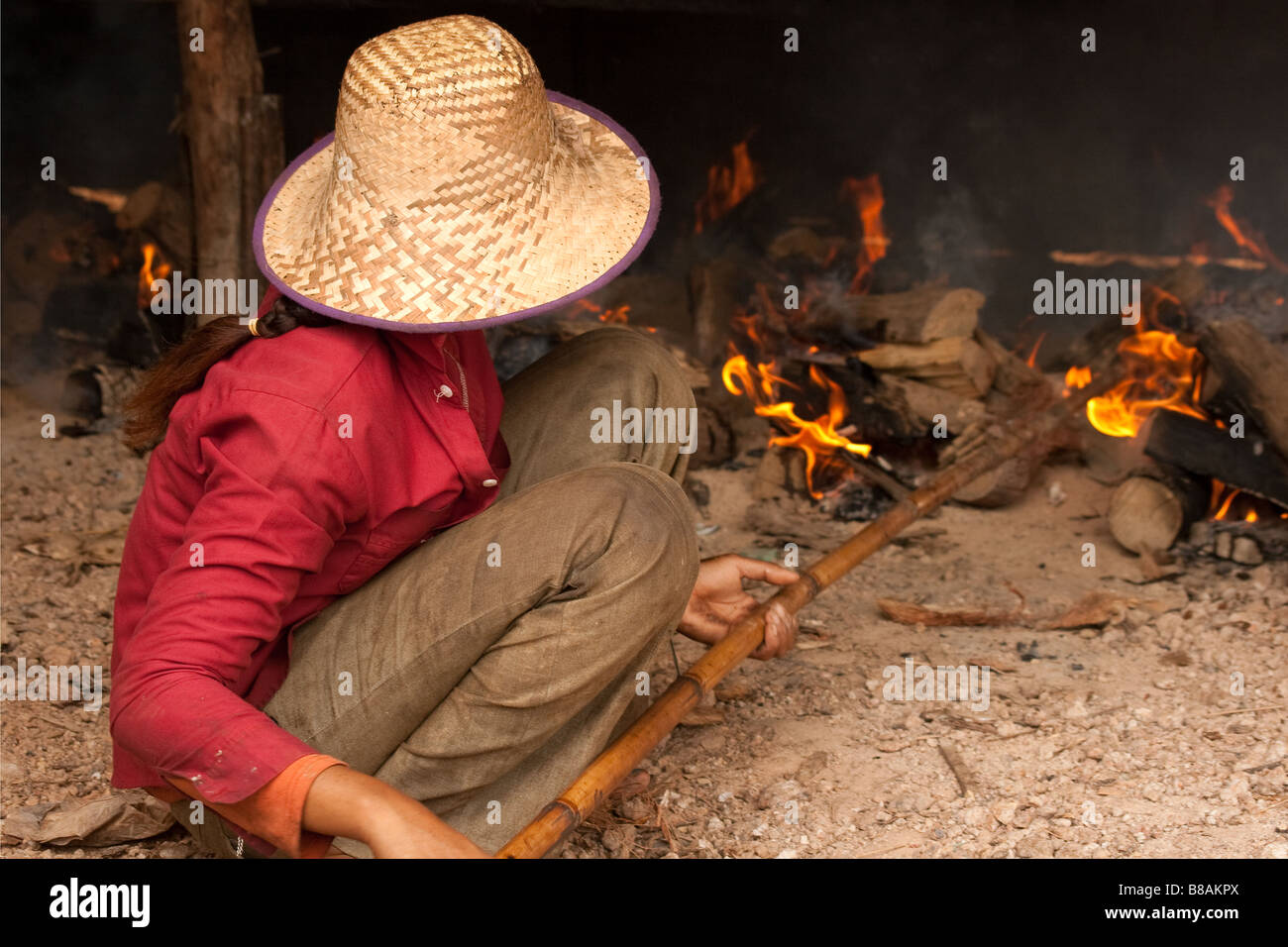 Cambodian girl stoking the fires that smoke the fish using traditional methods at an impoverished village on the Mekong river (Cambodia) Stock Photo