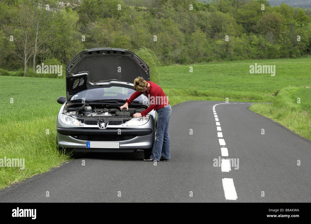 Woman alone with her broken down car on a country road Stock Photo