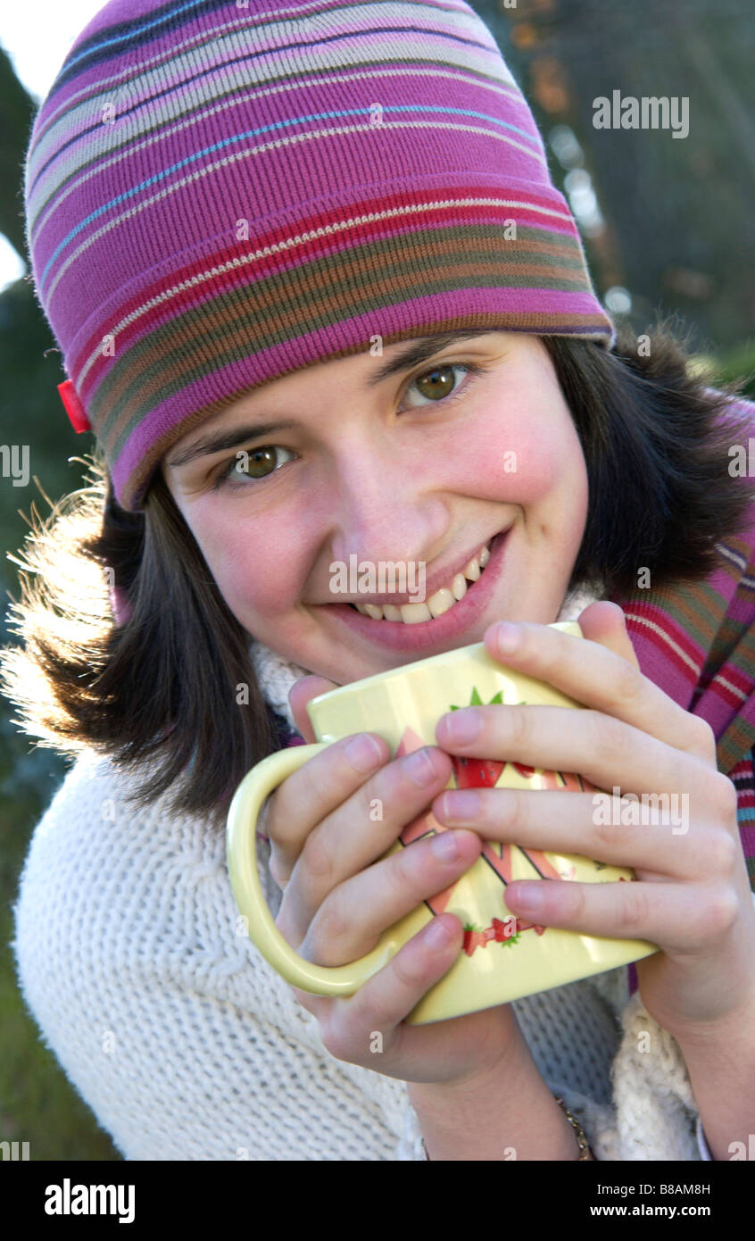 Portrait of girl drinking coffee / tea to keep warm outside in winter Stock Photo
