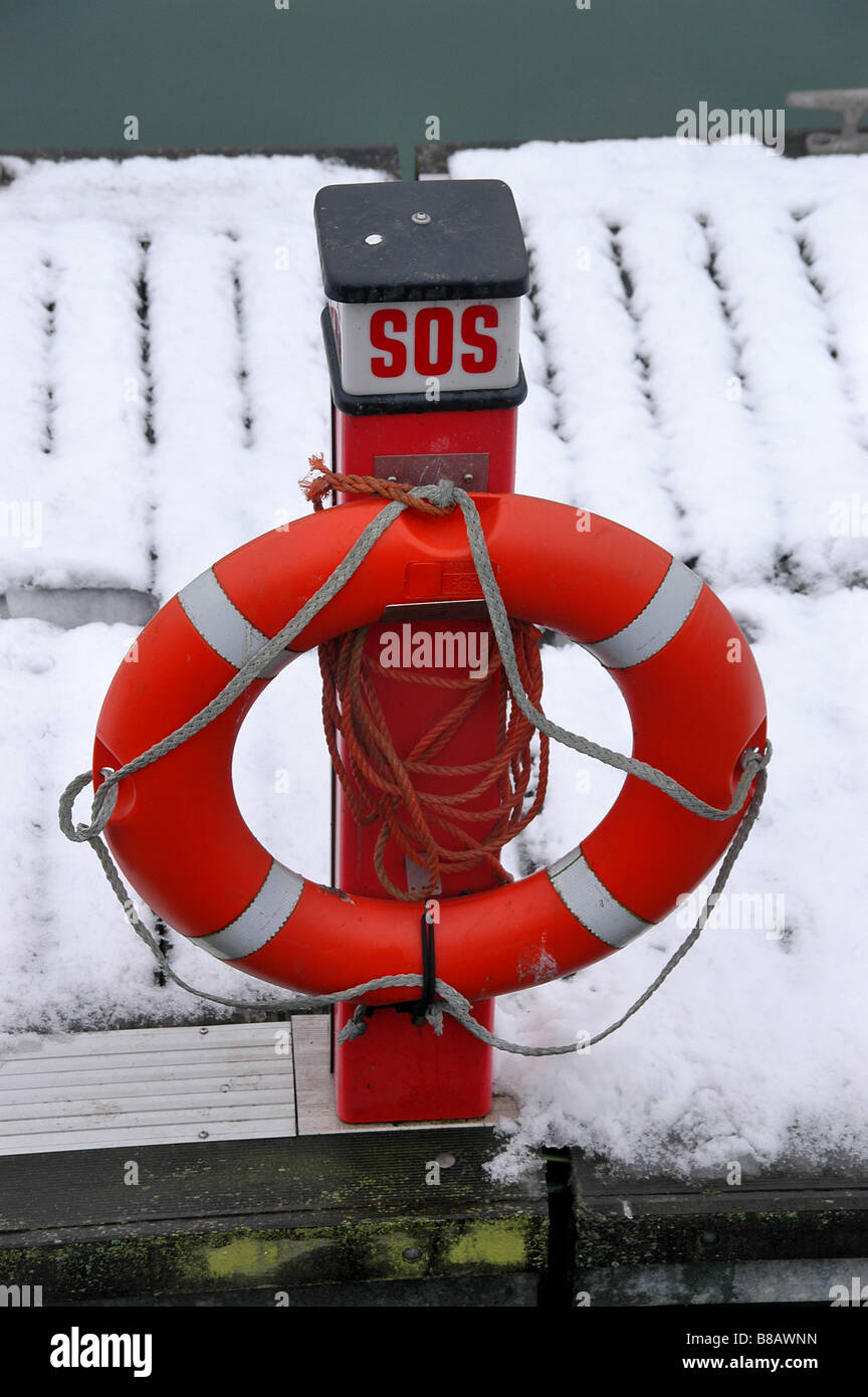 A SOS post with a lifebelt at a snowy harbour. Stock Photo
