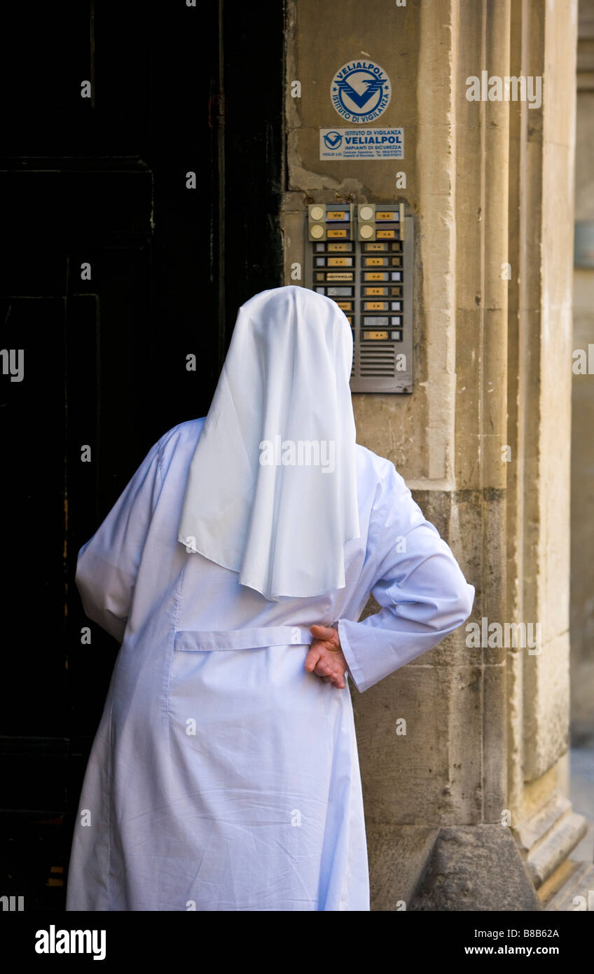 Nun dressed in white looking for door bell Lecce Puglia Italy Stock Photo