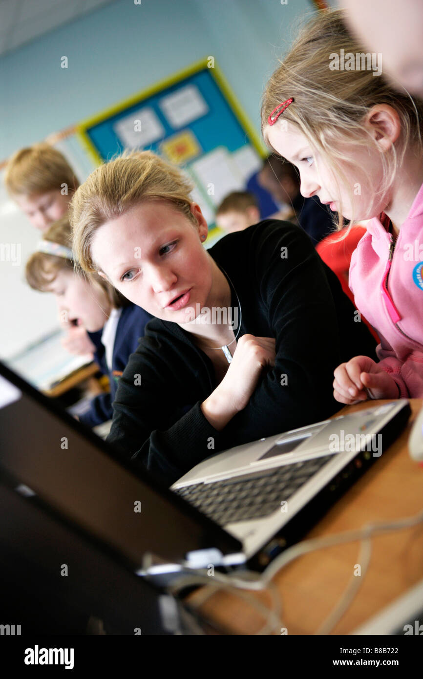 teacher working with primary school pupils on laptop computer Stock ...