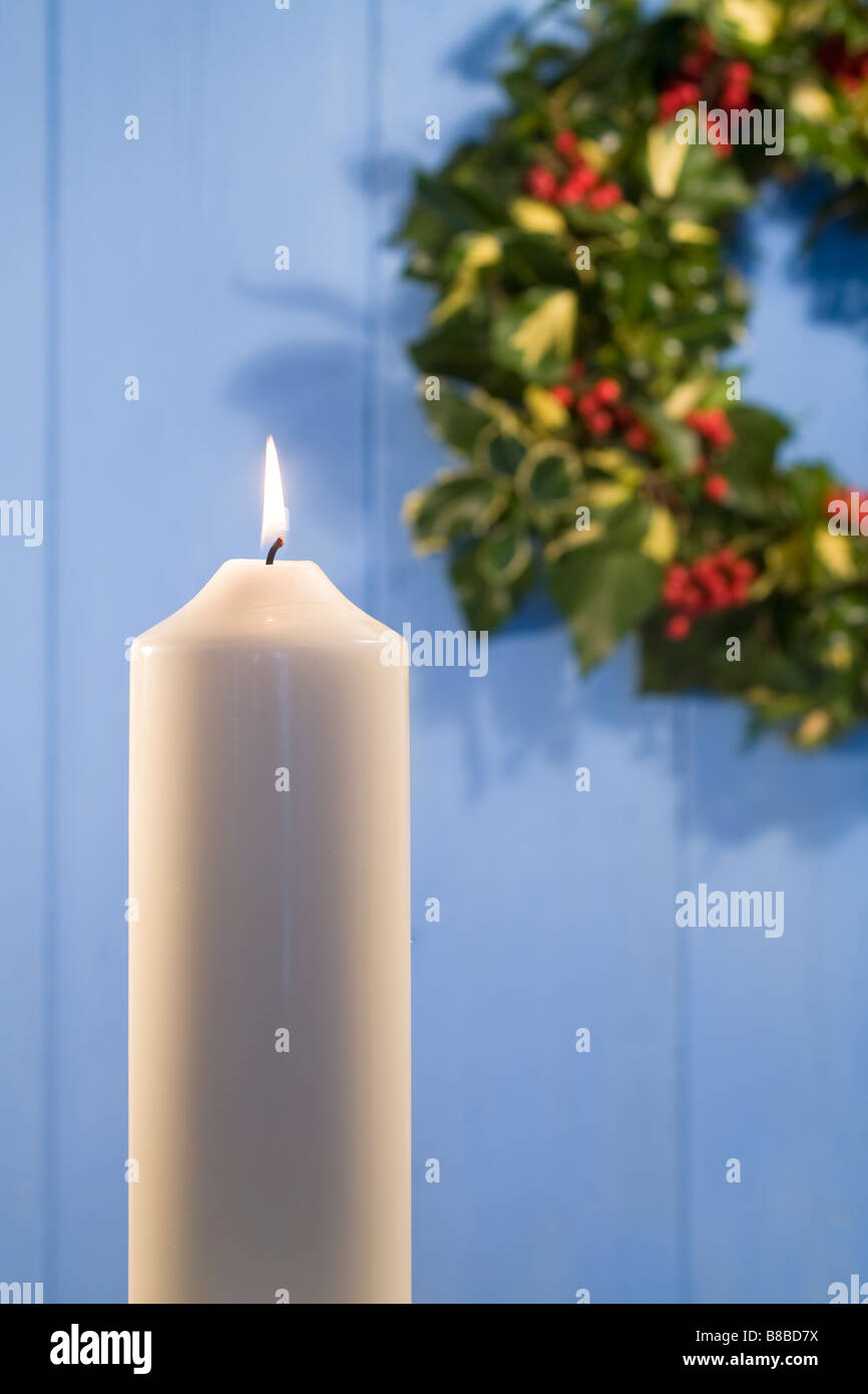 White Christmas Candle and Holly Wreath on Blue Door Stock Photo