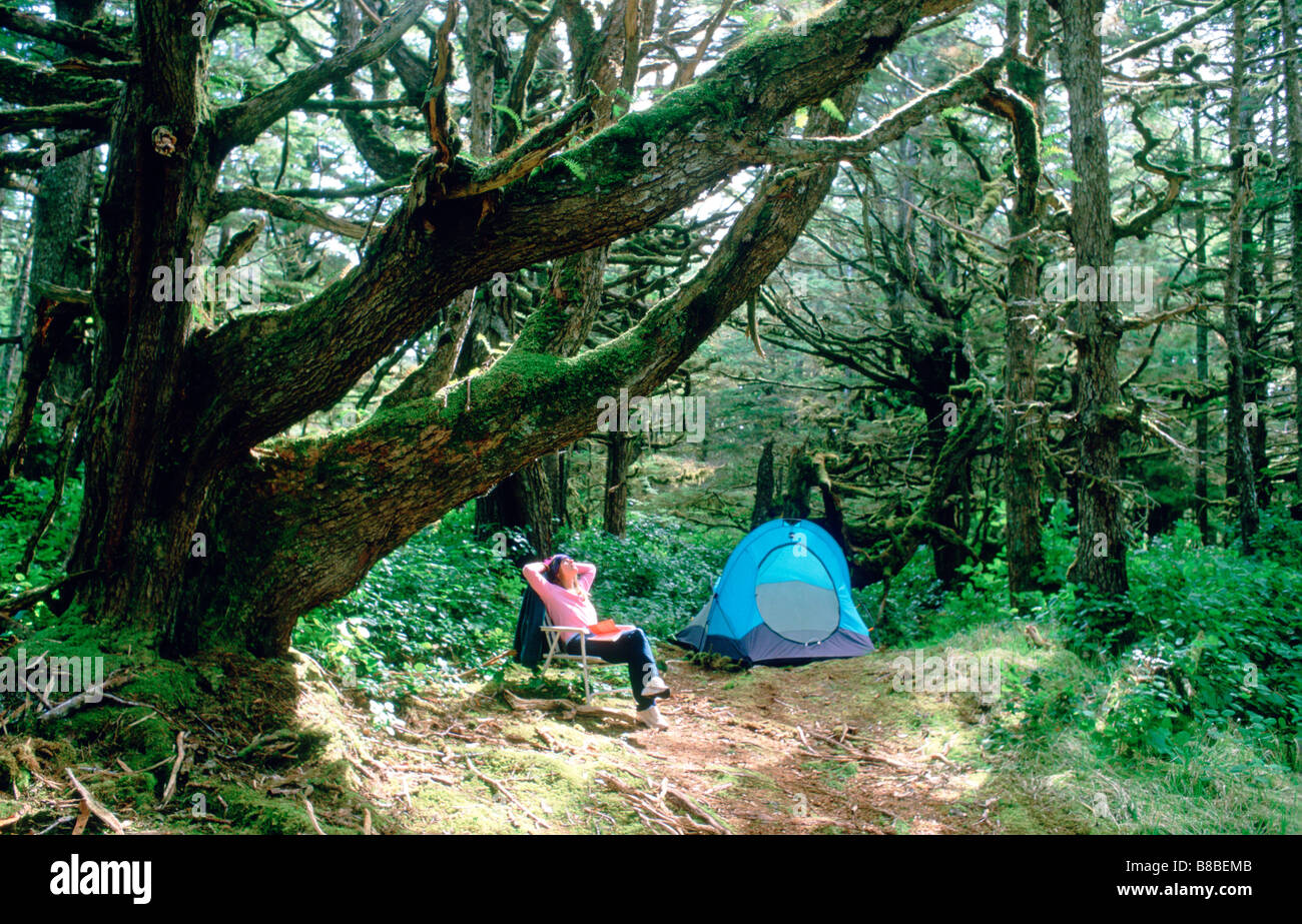 Woman Relaxing by Tent, Old Growth est, Naikoon Provincial Park, British Columbia Stock Photo
