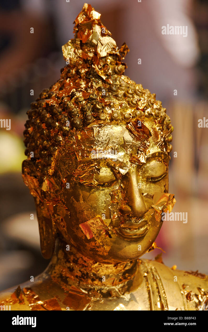 Face of Buddha statue with pieces of gold leaf offerings - Wat Phra Kaew and the Grand Palace in central Bangkok Thailand Stock Photo