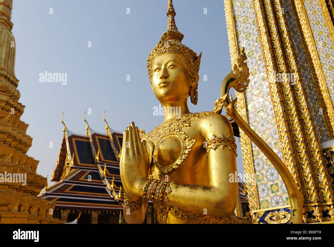 Golden Kinnara statue forming a Wai hand gesture - Wat Phra Kaew and the Grand Palace in central Bangkok Thailand Stock Photo
