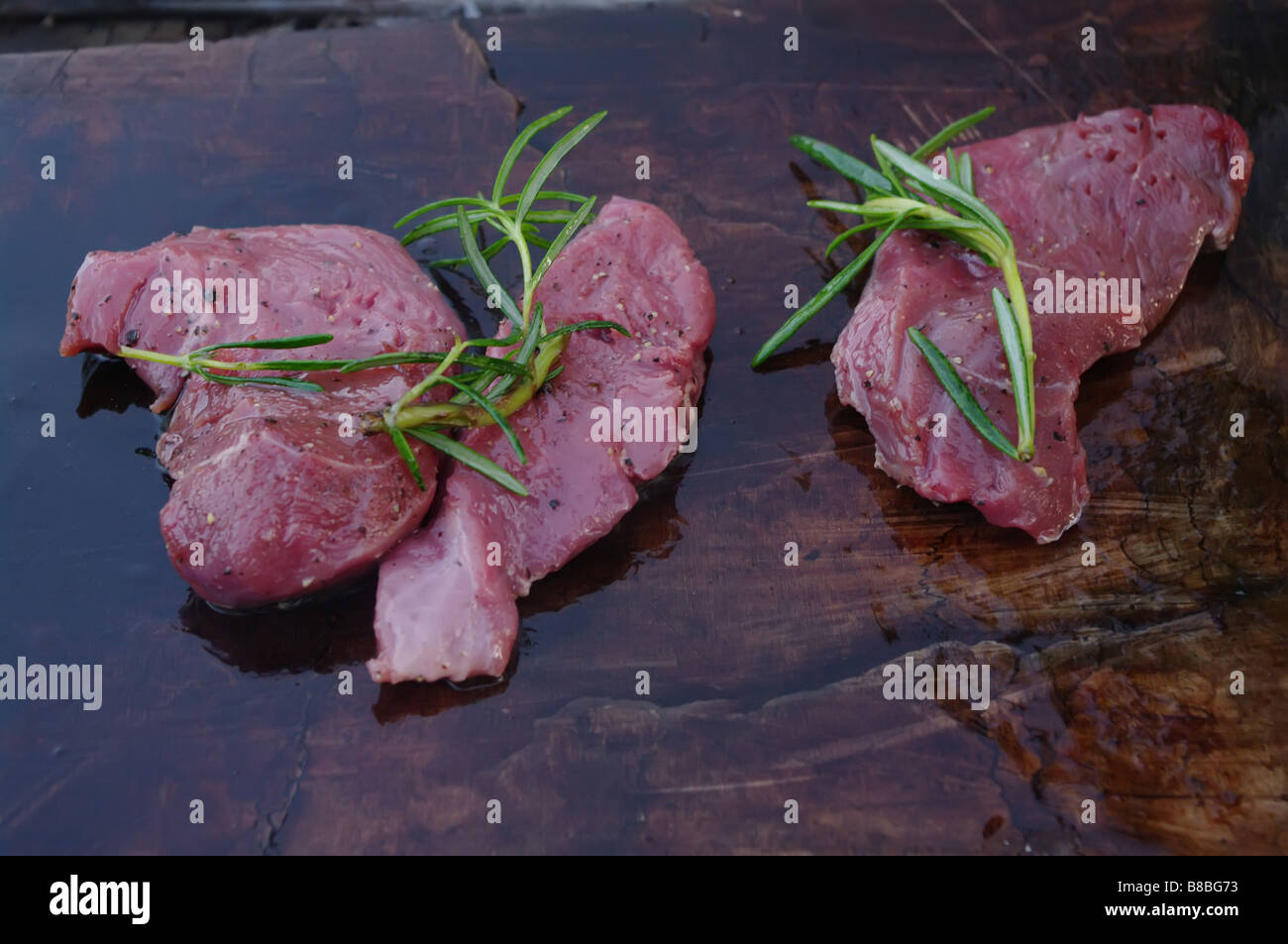 deer meat on bbq flagstone with rosemary Stock Photo Alamy