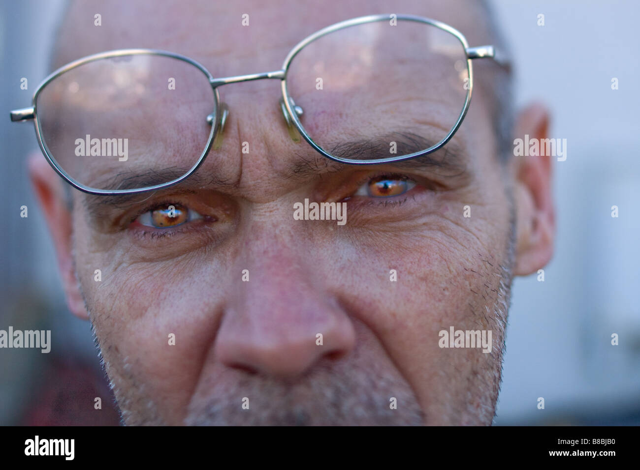 A man with striking brown eyes and reading glasses on head with serious look Stock Photo