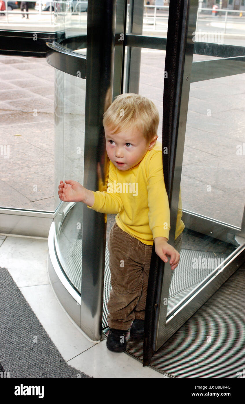 Boy Using Revolving Door fice Tower Stock Photo