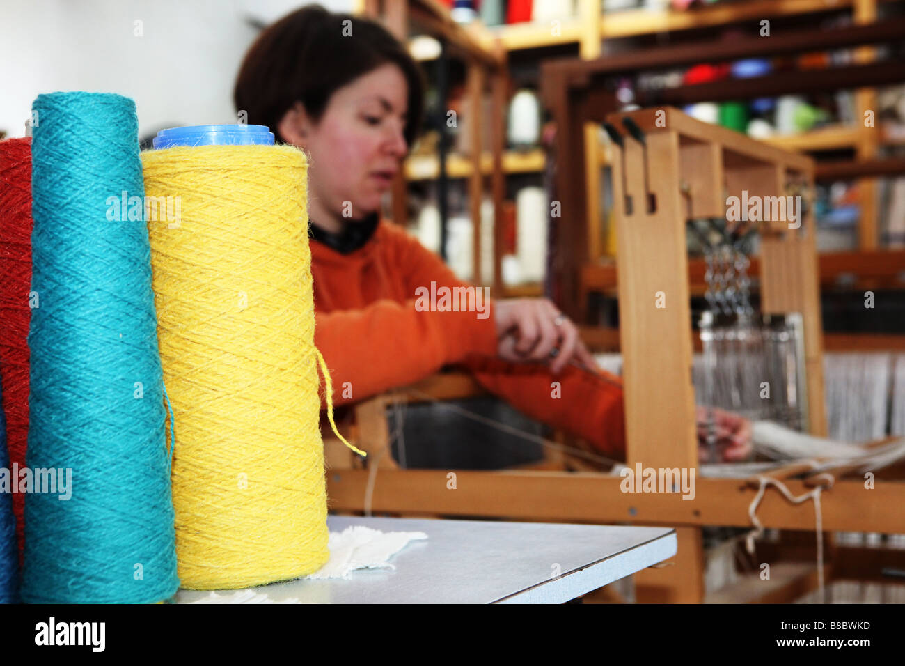 Closeup of bright coloured hand weaving cotton threads with hand weaver in background working on traditional wooden machine Stock Photo