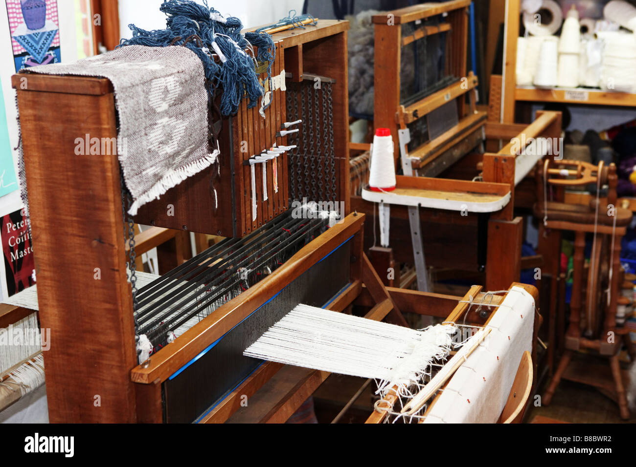 Traditional wooden hand weaving machines next to each other in a small