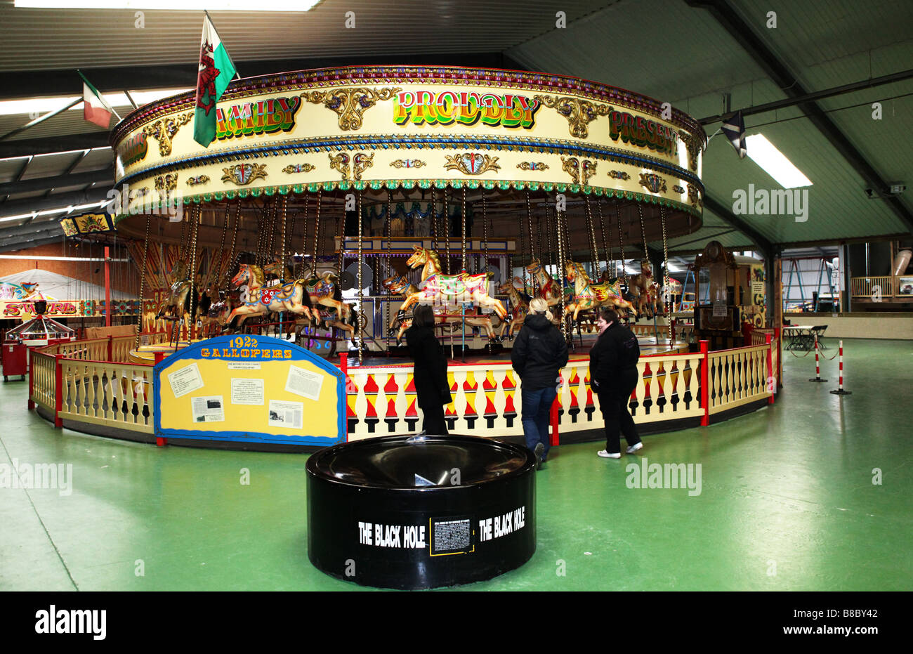 A traditional wooden merry go round fair ground ride galloping horse carousel indoors large warehouse UK Stock Photo