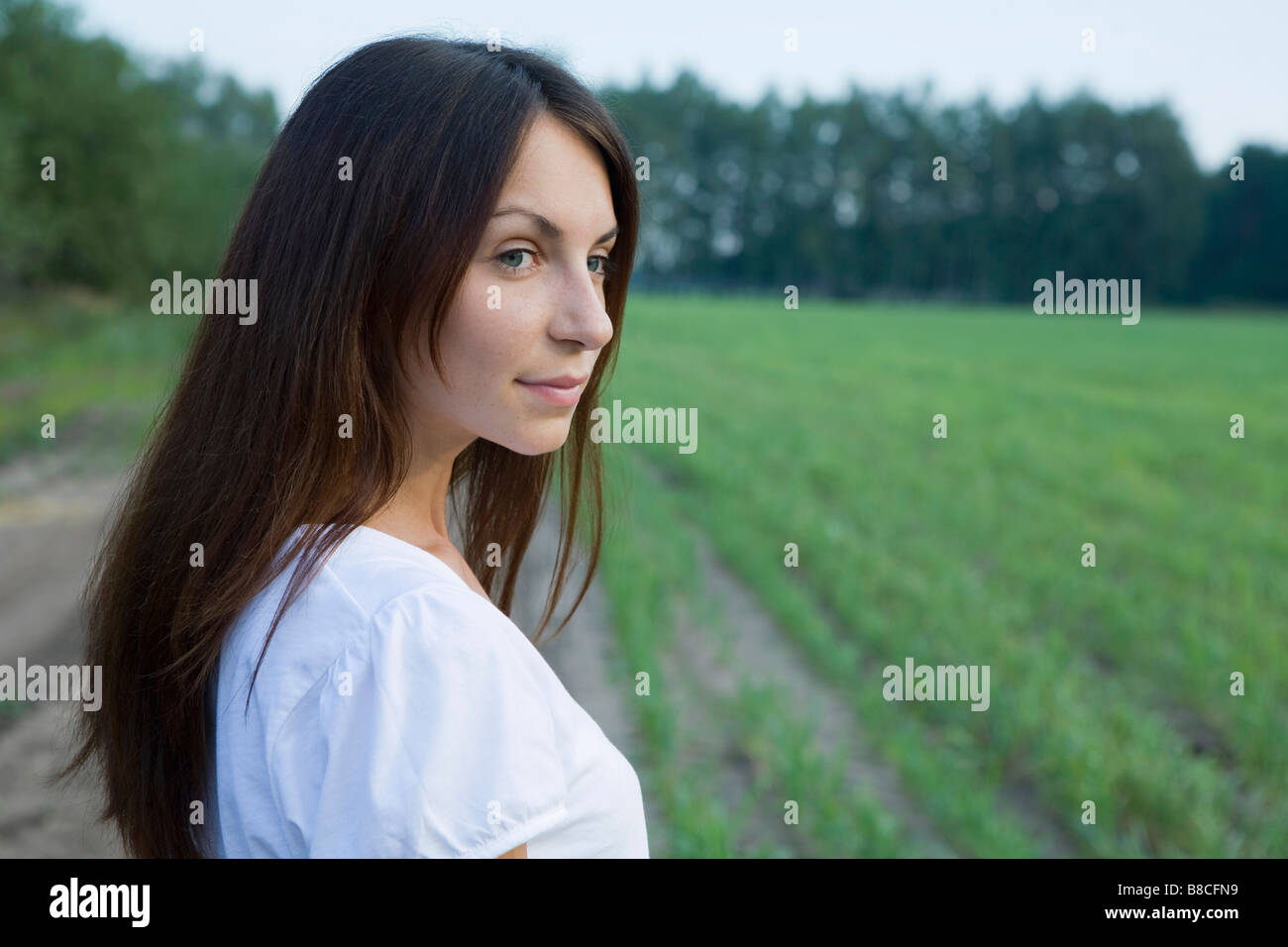 Young woman standing on field Stock Photo - Alamy