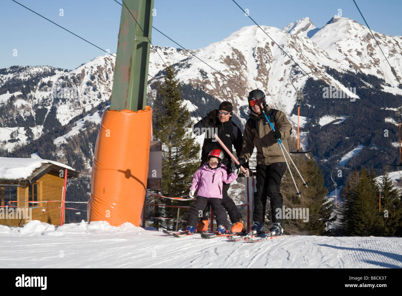 Rauris Austria EU January Two men and a little girl ascending to the slopes using a ski tow Stock Photo
